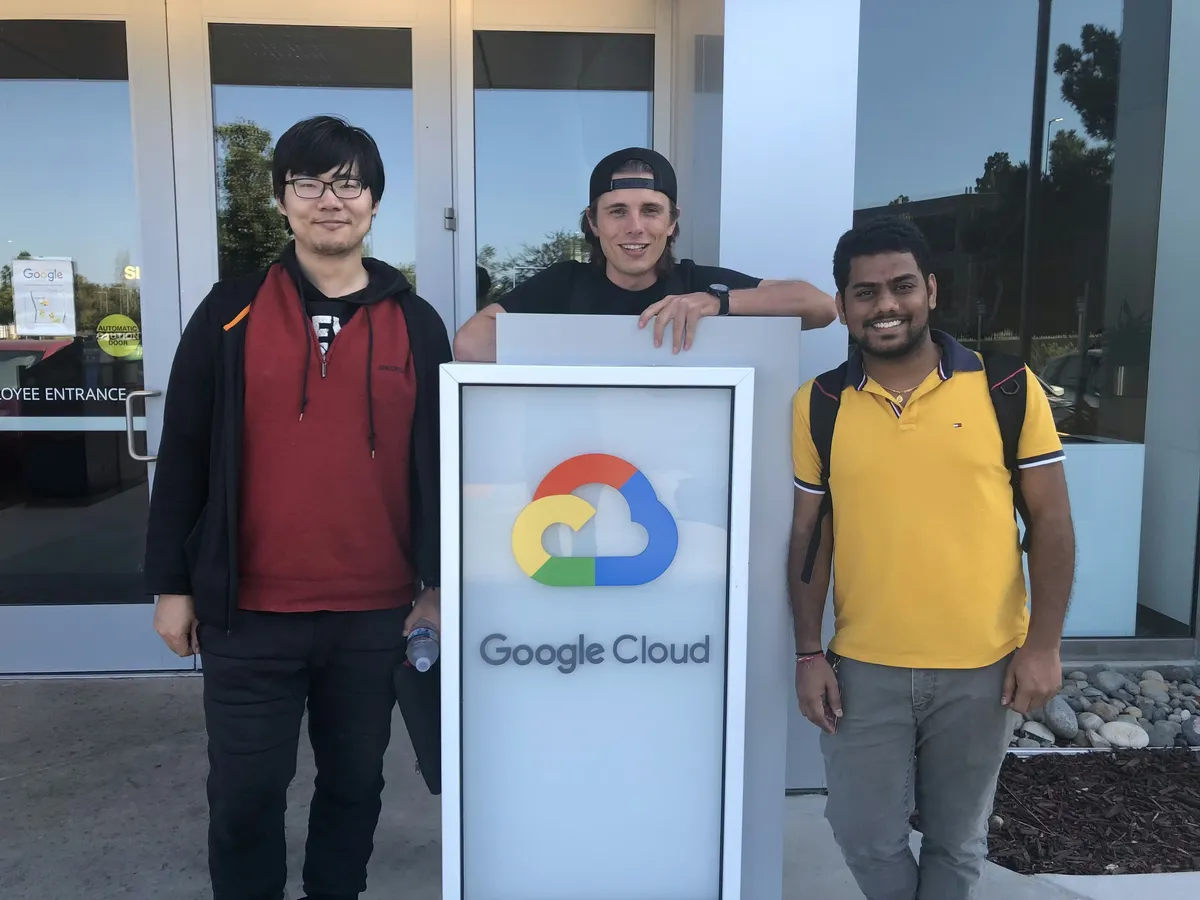 Two other engineers and myself smiling and standing in front of the Google Cloud office.